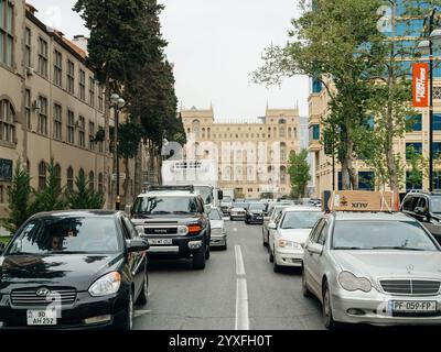 Bakou, Azerbaïdjan - 3 mai 2019 : une rue urbaine animée à Bakou bordée de voitures et de bâtiments historiques, menant à la grande Maison du gouvernement en arrière-plan. Banque D'Images