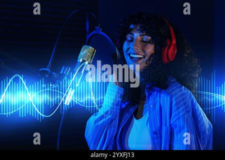 Chanteur chantant dans le microphone dans un studio d'enregistrement professionnel. Ondes sonores Banque D'Images