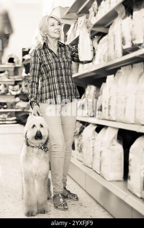 Femme achetant de la nourriture pour animaux de compagnie pour chiot berger afghan dans la boutique pour l'animal Banque D'Images