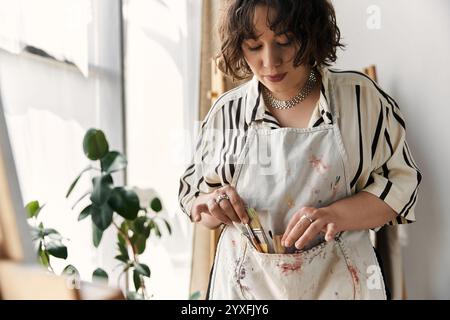 Une jeune artiste talentueuse aux cheveux bouclés peint passionnément tout en étant nichée dans son appartement élégant. Banque D'Images