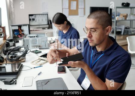 Ingénieurs assemblant un appareil électronique dans un environnement de bureau Banque D'Images