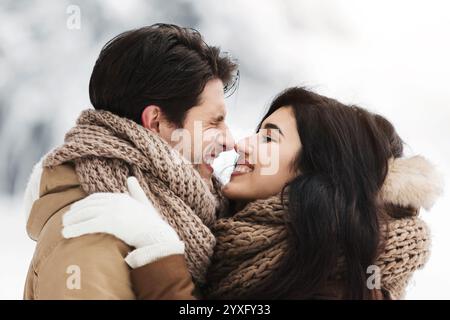 Les amoureux mignon Frotter leur nez embrassant debout dans le parc enneigé Banque D'Images