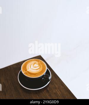 tasse à café blanche placée sur une table en bois près d'une fenêtre lumineuse, capturant un moment serein de simplicité moderne et de lumière naturelle. Parfait pour les vacances pr Banque D'Images