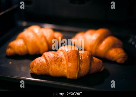 Trois croissants sont cuits dans le four de la maison de près. Photographie culinaire Banque D'Images