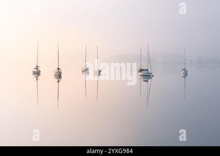 Rangée de voiliers reflétant dans le lac calme à Windermere dans le Lake District, Royaume-Uni. Banque D'Images
