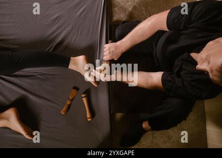 Un homme donne un massage thaïlandais relaxant des pieds avec un kit de massage Tok-Sen dans un spa de beauté. Soins corporels. Banque D'Images