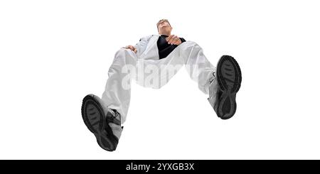 Image vue du bas d'un jeune homme à la mode en pantalon blanc et baskets noires, mettant en valeur l'énergie et le style sportif moderne. Confort et confiance Banque D'Images