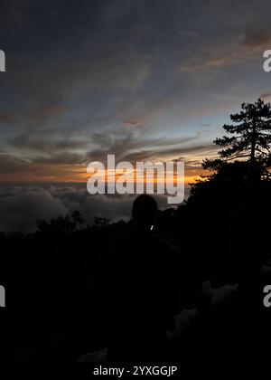 Cette superbe photographie capture la silhouette d'une personne regardant un coucher de soleil spectaculaire depuis un point de vue en haute altitude dans les montagnes Troodos, Chypre Banque D'Images