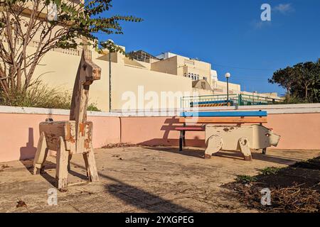 Ancienne aire de jeux avec des structures animales en bois altérées dans le quartier résidentiel pendant le coucher du soleil doré Banque D'Images