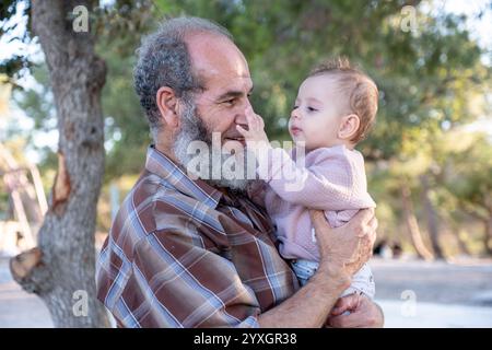 Un moment chaleureux et affectueux entre un grand-père et son petit-enfant, profitant de moments de qualité ensemble en plein air dans un cadre naturel. La scène capture lo Banque D'Images