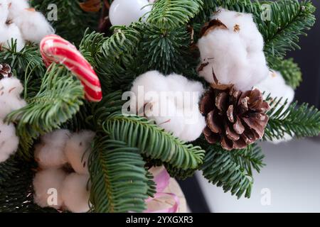 Gros plan de la belle composition florale d'hiver de Noël avec des fleurs de coton, des branches d'épinette et des cônes d'épinette. Banque D'Images