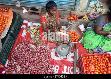 Vendeur utilisant des balances pour peser les tomates au marché aux légumes dans le district de Triplicane de Chennai, Tamil Nadu, Inde Banque D'Images