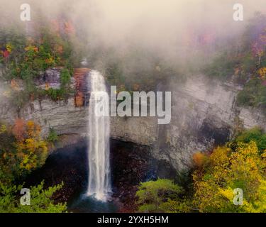 Entourée d'un riche feuillage automnal et d'un épais brouillard, la cascade du parc d'État de Fall Creek Falls dans le Tennessee descend en cascade au-dessus d'une falaise rocheuse dans un bassin sombre. Banque D'Images