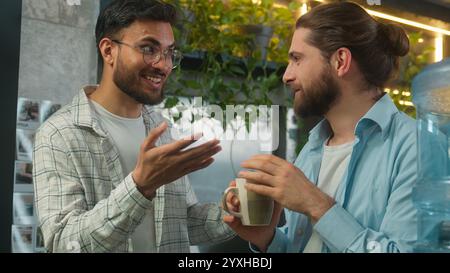 Hommes multiethniques Caucasien Indien deux gars hommes amis de bureau collègues d'affaires amicaux insouciants parler heureux hommes d'affaires parlant rire Banque D'Images