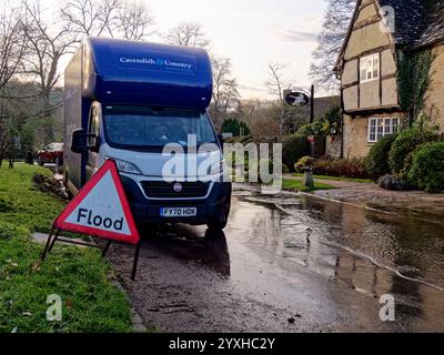 Panneau d'avertissement d'inondation sur le côté de la route devant la fourgonnette d'enlèvement avec une grande flaque d'eau après l'inondation à Minster Lovell, Witney, Oxfordshire, Angleterre, Royaume-Uni Banque D'Images