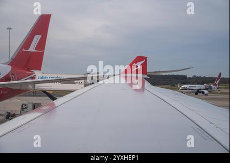 02.11.2024, Melbourne, Victoria, Australie - Blick aus einem Passagierflugzeug vom Typ Airbus A330-200 der australischen Fluggesellschaft Qantas Airways auf die Tragflaeche und Winglet mit dem kultigen logo des Flying Kangaroo. Liens daneben sieht man das Seitenleitwerk eines Flugzeugs der chinesischen Shanghai Airlines. *** 02 11 2024, Melbourne, Victoria, Australie vue d'un Airbus A330 200 de passagers de la compagnie aérienne australienne Qantas Airways sur l'aile et l'ailette avec le logo emblématique du kangourou volant sur la gauche, vous pouvez voir le stabilisateur vertical d'un avion du CH Banque D'Images