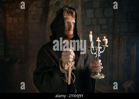 Portrait de moine à capuche en costume médiéval tenant une croix en bois et un chandelier Banque D'Images