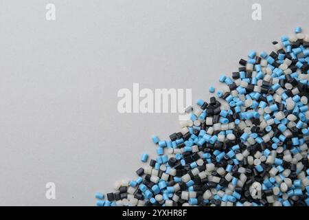 Pile de granulés de plastique colorés sur fond gris, vue de dessus. Espace pour le texte Banque D'Images