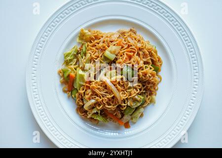 Nouilles Yakisoba sur une table blanche、vue de dessus、nouilles sautées traditionnelles japonaises avec de la viande, des légumes et une sauce spéciale Banque D'Images