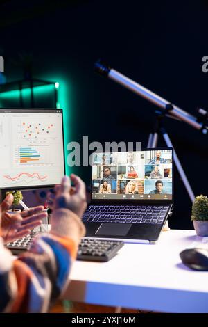 Brandissant de son appartement, homme noir utilisant un ordinateur portable pour participer à des réunions en ligne. Les indépendants masculins utilisent la technologie sans fil pour la visioconférence avec leurs collègues afin de discuter du travail à distance. Banque D'Images