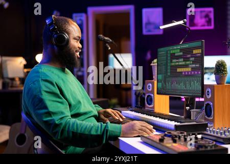 Producteur de musique éditant de vieux enregistrements audio sur un logiciel professionnel, fonctionnant sur console de mixage et équipement stéréo. Ingénieur du son produisant de nouvelles chansons avec des airs acoustiques dans le home studio. Banque D'Images