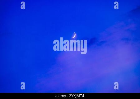 Conjonction du croissant de lune ciré avec Vénus dans les nuages crépusculaires. Banque D'Images