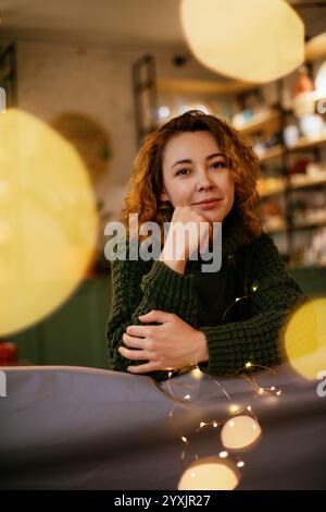 Femme d'âge moyen souriante profitant des vacances confortables de Noël et du nouvel an. Moment de vacances chaleureux et festif avec une femme caucasienne entourée de Christma Banque D'Images