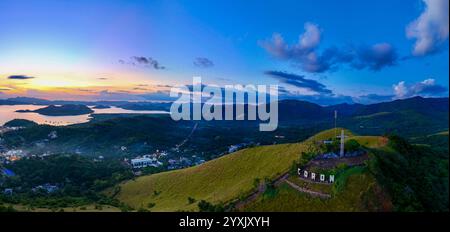 Une vue aérienne panoramique à couper le souffle de Coron, Philippines, capturée lors d'un coucher de soleil vibrant. L'image montre des collines verdoyantes, une grande croix an Banque D'Images