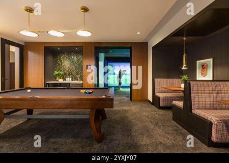 Billard et salle de jeux dans le complexe d'appartements avec l'homme à l'aide d'un simulateur de golf Banque D'Images