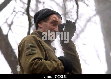 RÉGION DE KHARKIV, UKRAINE - 11 DÉCEMBRE 2024 - Un soldat de la 211e Brigade du pont ponton des forces de soutien des forces armées ukrainiennes frotte un œil en fumant lors de la construction de fortifications dans le secteur de Kharkiv, région de Kharkiv, dans le nord-est de l'Ukraine. Banque D'Images