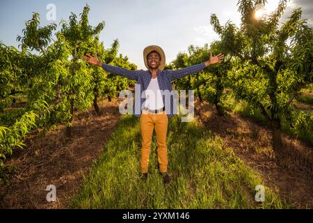 Portrait d'agriculteur afro-américain dans son verger. Il cultive des prunes. Agriculteur prospère debout dans le verger. Banque D'Images