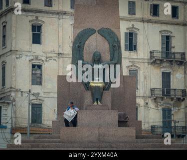 Le monument Saad Zaghloul Pacha à Alexandrie, en Égypte, présente une statue féminine ailée à sa base, avec des bâtiments coloniaux anciens comme toile de fond. Banque D'Images