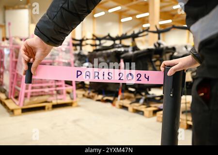 Kaiserslautern, Allemagne. 17 décembre 2024. Un employé tire une bande barrière portant l'inscription « Paris 2024 » du rayonnage d'un entrepôt. Des milliers d'articles des Jeux olympiques d'été à Paris sont remis d'un entrepôt aux soumissionnaires retenus après une vente aux enchères sur Internet. Une entreprise avait acheté 50 000 articles - des canapés aux parasols et des chaises d'arbitre au baby-foot - pour donner une seconde vie au matériel. Crédit : Uwe Anspach/dpa/Alamy Live News Banque D'Images