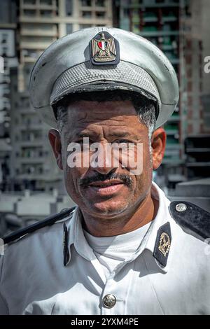 Portrait en gros plan d'un policier égyptien à Alexandrie, Egypte. Il se tient confiant en uniforme avec un paysage urbain derrière lui, la sécurité. Banque D'Images