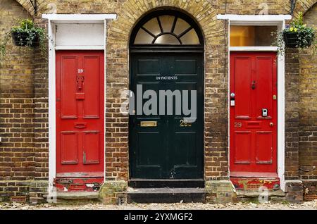 Porte vitrée PedimentGreen arquée Sun Burst avec signe hospitalier flanqué de deux portes rouges, Eton, Royaume-Uni, contraste de couleur, coloré Banque D'Images