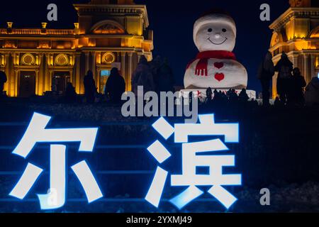 Harbin, province chinoise du Heilongjiang. 17 décembre 2024. Les touristes sont photographiés devant un bonhomme de neige géant à Harbin, dans la province du Heilongjiang du nord-est de la Chine, le 17 décembre 2024. Crédit : Zhang Tao/Xinhua/Alamy Live News Banque D'Images