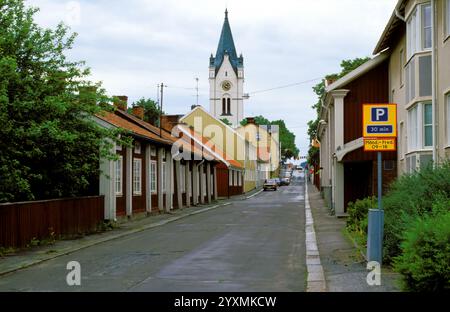 Orebro, Suède – 1986. Petite rue de ville à Nora, Suède. Panneaux, vieux bâtiments en bois et une tour d'église, été et couvert. Utilisation éditoriale. Banque D'Images