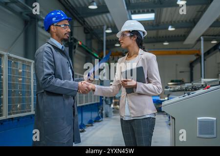 Gestionnaire indienne et ingénieur en chef afro-américain marchant à travers l'usine, parlant et planifiant l'optimisation de la production, vue de face. Banque D'Images