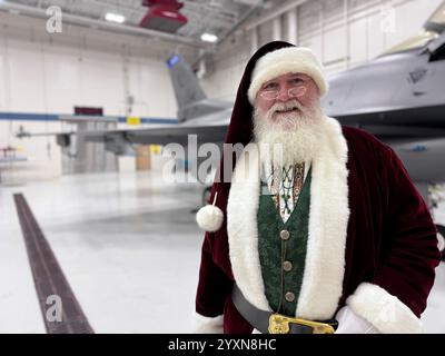 Le Père Noël pose pour une photo avec un F-16 Fighting Falcon affecté à la 148th Fighter Wing, Minnesota Air National Guard, le 13 décembre 2024. Père Noël Banque D'Images