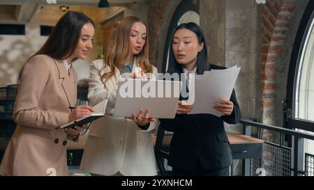 Groupe entreprise remue-méninges femmes d'affaires trois femmes multiraciales multiethniques diversité femmes d'affaires asiatiques filles caucasiennes dans des documents de bureau Banque D'Images