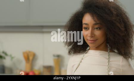 Heureux sourire sain afro-américain femme au foyer chef fille ethnique femme à la maison cuisine moderne mis sur tablier travail de maison de ménage se préparer à Banque D'Images