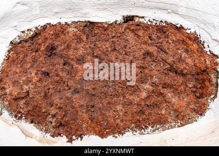 Une surface brune et blanche avec un trou au milieu. Le trou est entouré de beaucoup de saleté brune Banque D'Images