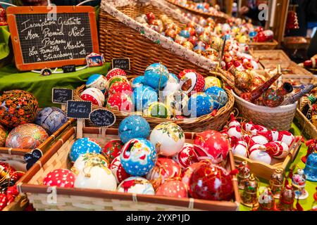 Strasbourg, France - 6 décembre 2024 : décorations de boules de Noël mâchées en papier peint à la main en vente sur un stand au marché de Noël Banque D'Images