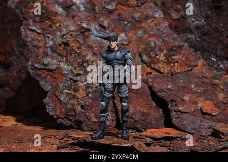 Metal Gear Solid action figure scène extérieure fond en métal rouillé vue complète Banque D'Images