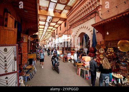 moto conduisant le long de la rue couverte dans le souk avec des boutiques d'artisanat sur la rue fehl chidmi marrakech, maroc Banque D'Images