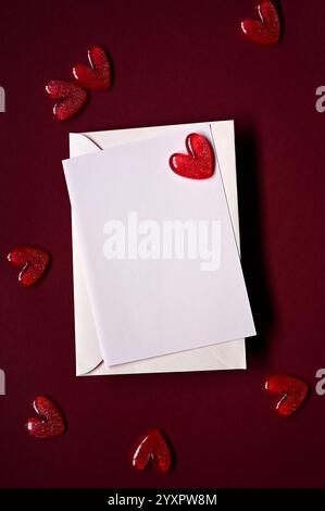 Enveloppe et coeurs rouges sur fond rouge. Vue de dessus. Saint-Valentin. Banque D'Images