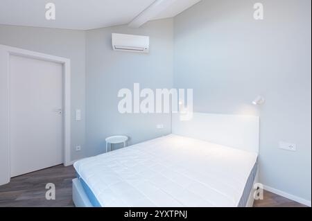 Chambre lumineuse et propre avec un lit confortable, armoire encastrée blanche, puits de lumière et design minimaliste, atmosphère pour une détente parfaite. Min. Moderne Banque D'Images