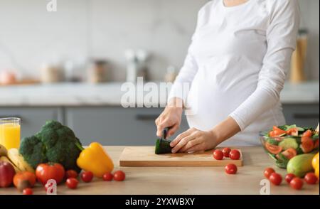 Femme enceinte préparant une salade saine dans un cadre de cuisine moderne Banque D'Images