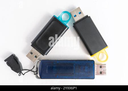 Divers lecteurs flash USB de différentes couleurs et conceptions sont placés sur une surface blanche, mettant en valeur leurs capacités de stockage et des styles uniques, idéal Banque D'Images
