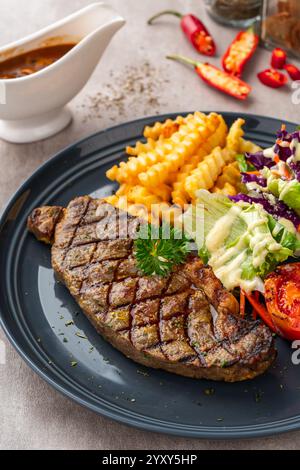 Steak de bœuf d'aloyau grillé avec frites et salades. Banque D'Images